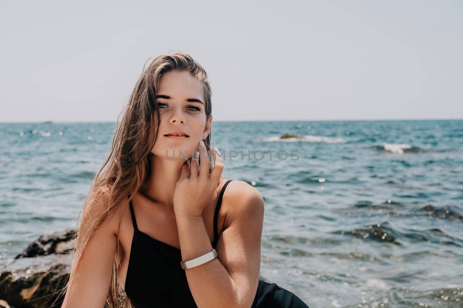 Woman summer travel sea. Happy tourist in hat enjoy taking picture outdoors for memories. Woman traveler posing on the beach at sea surrounded by volcanic mountains, sharing travel adventure journey by panophotograph