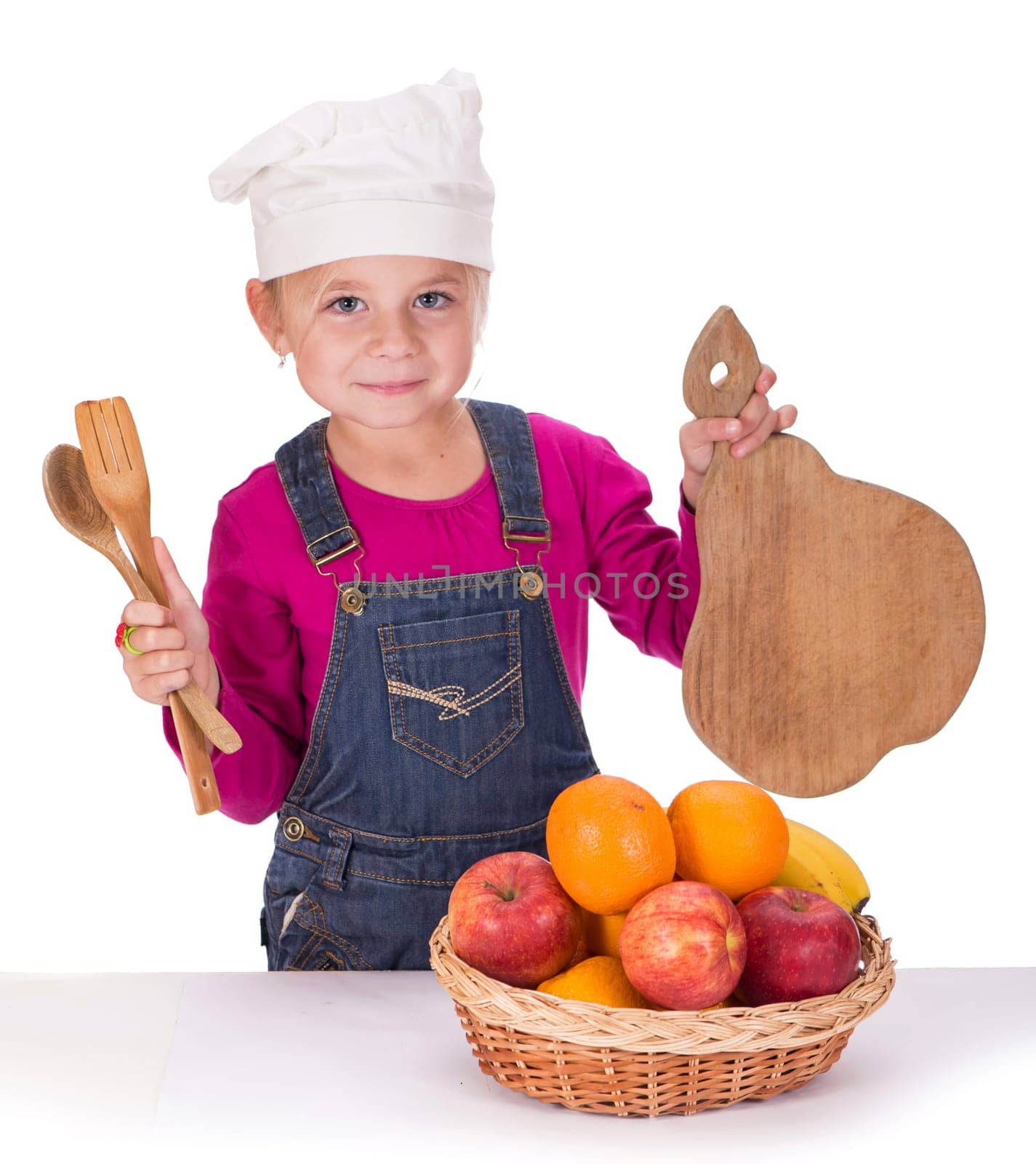 Close-up portrait of a little girl holding fruits - apples, bananas and oranges and kitchen appliances. Isolated on a light background. by aprilphoto