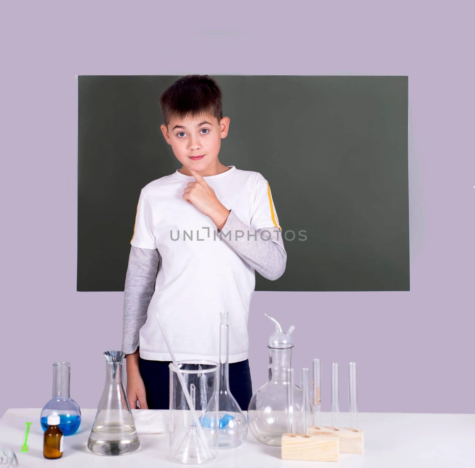 Portrait of school boy making chemical experiments with multicolored liquid in test tubes