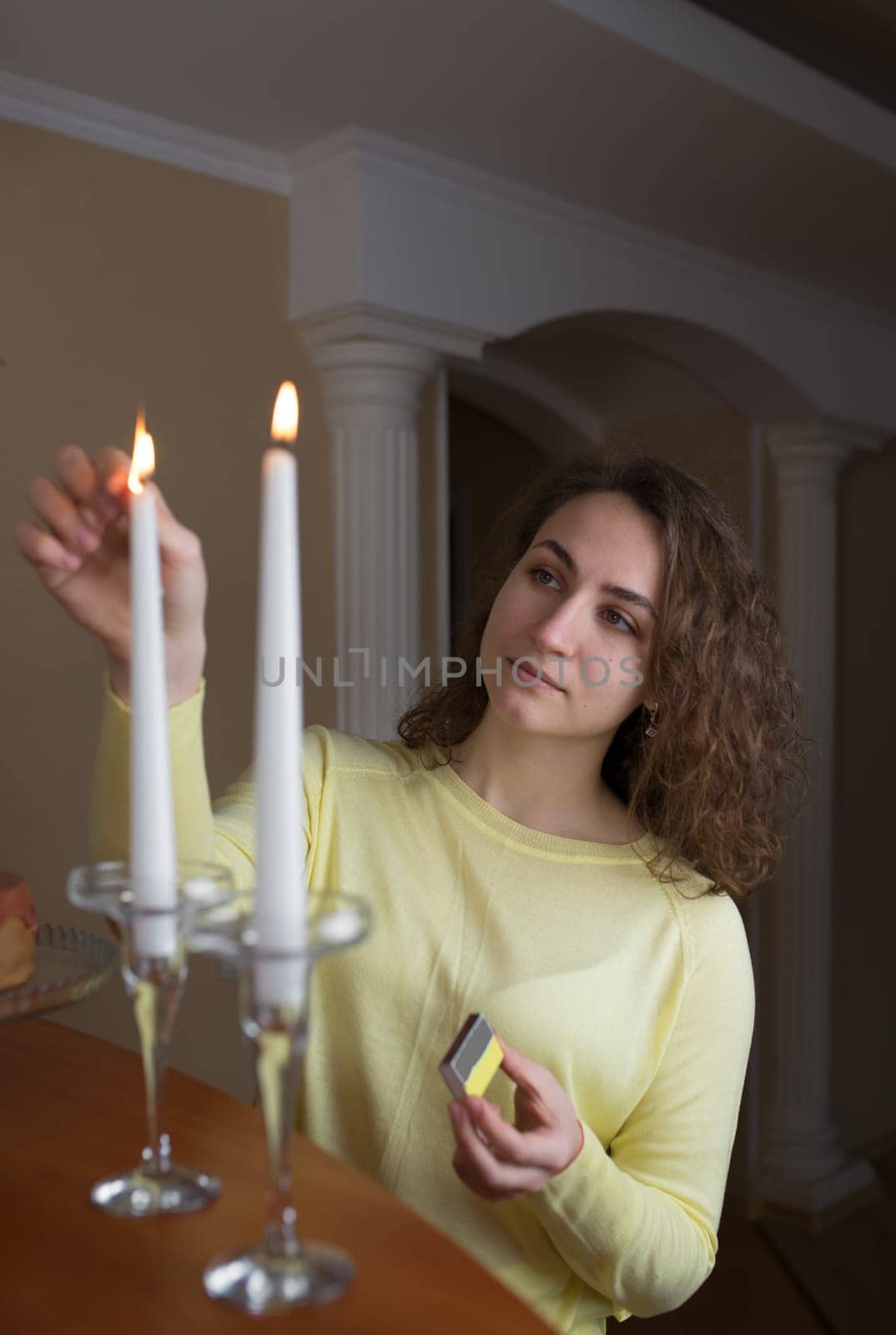 young girl with long hair lights candles in the kitchen at home by aprilphoto