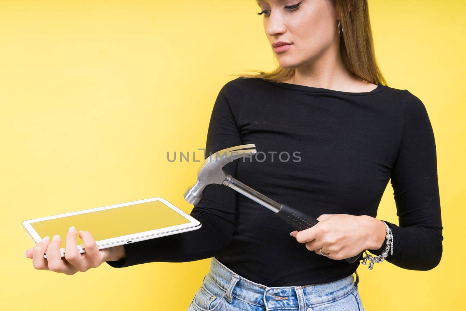 Service center. Laptop Repair. Female screwdriver unscrews laptop bolts on a yellow background