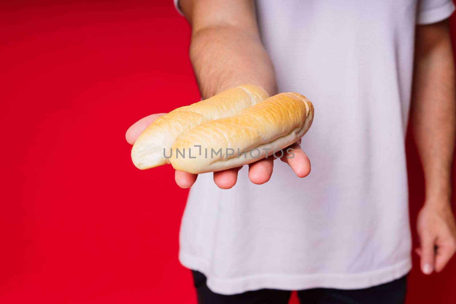 Man with freshly baked bread in hands isolated on red background studio