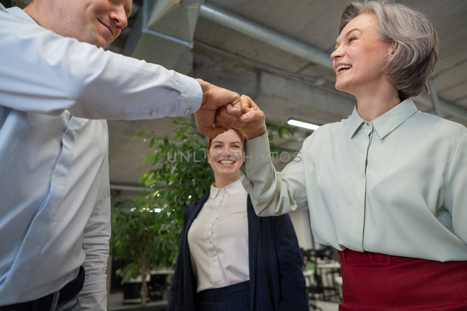 Caucasian man bumping his fists with colleagues as a sign of success. by mrwed54