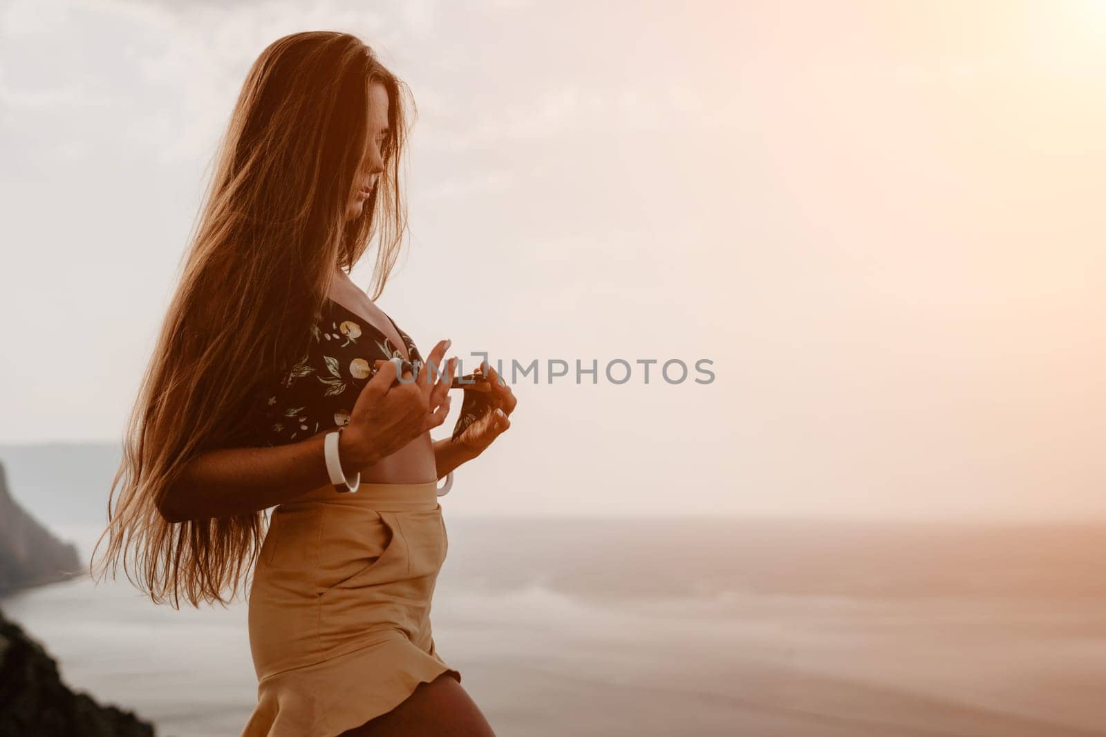 Woman travel sea. Happy tourist taking picture outdoors for memories. Woman traveler looks at the edge of the cliff on the sea bay of mountains, sharing travel adventure journey.