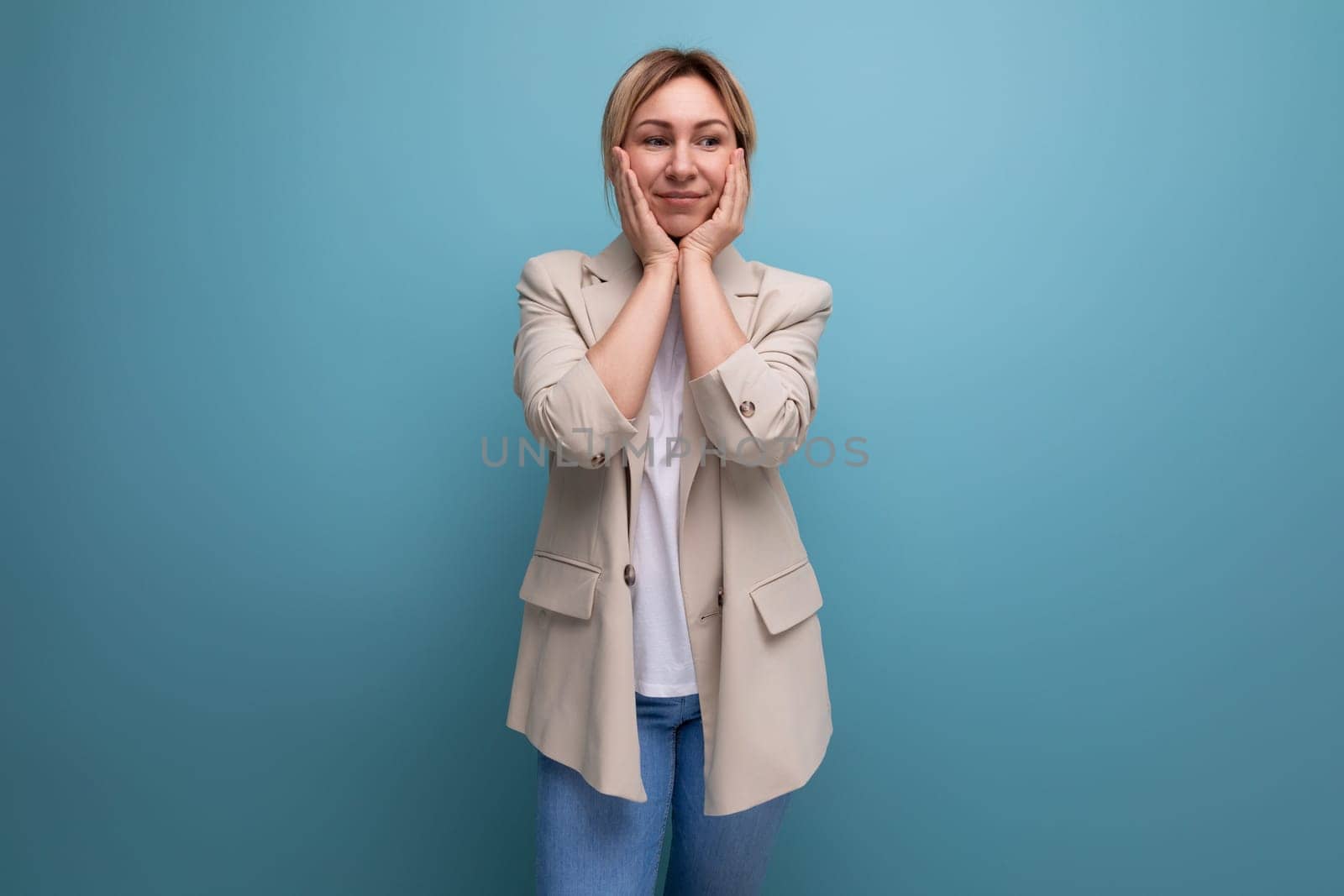 surprised blond young business woman in jacket on studio background.