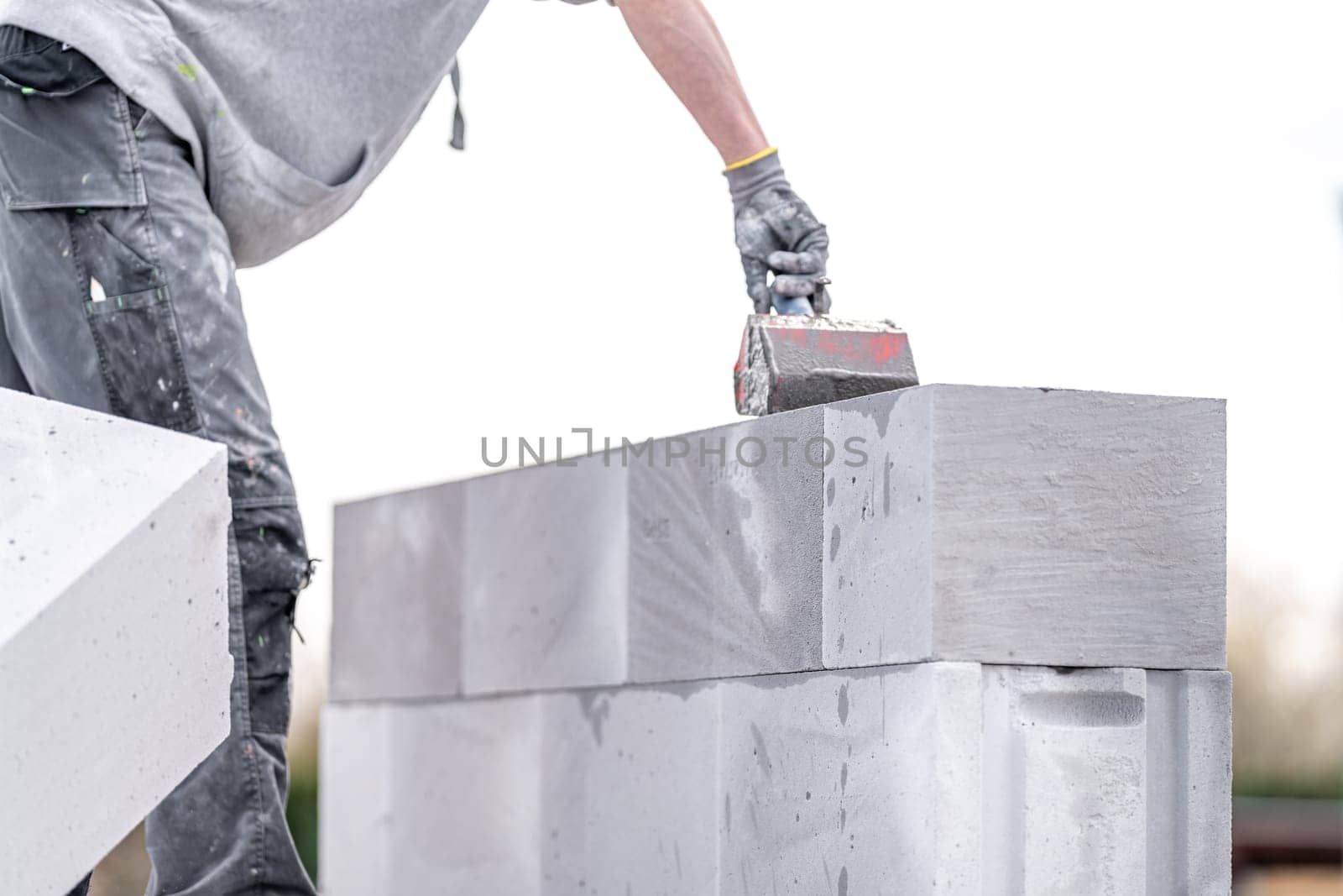 the mason applies glue to the concrete forms. construction of a wall of concrete bricks by Edophoto