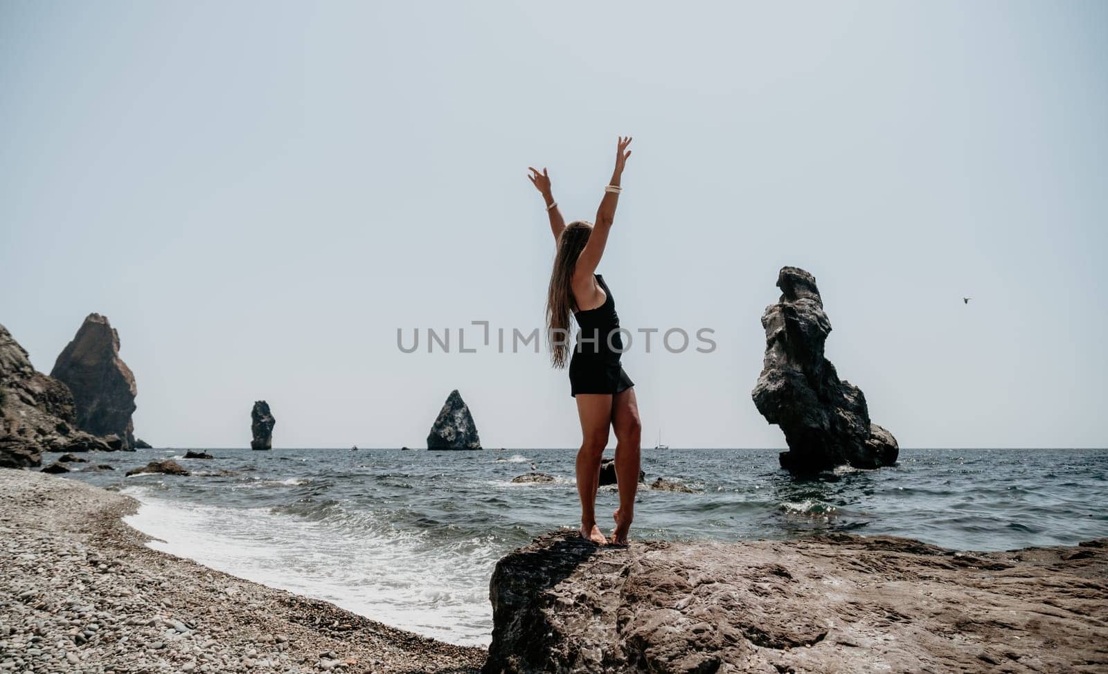 Woman summer travel sea. Happy tourist in hat enjoy taking picture outdoors for memories. Woman traveler posing on the beach at sea surrounded by volcanic mountains, sharing travel adventure journey by panophotograph