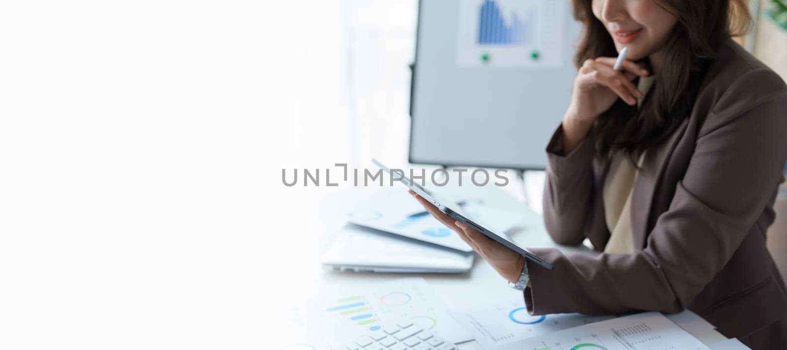 businesswoman in a black suit inside the office using tablet computer, audit paperwork for customers to contact, business people concept. by Manastrong