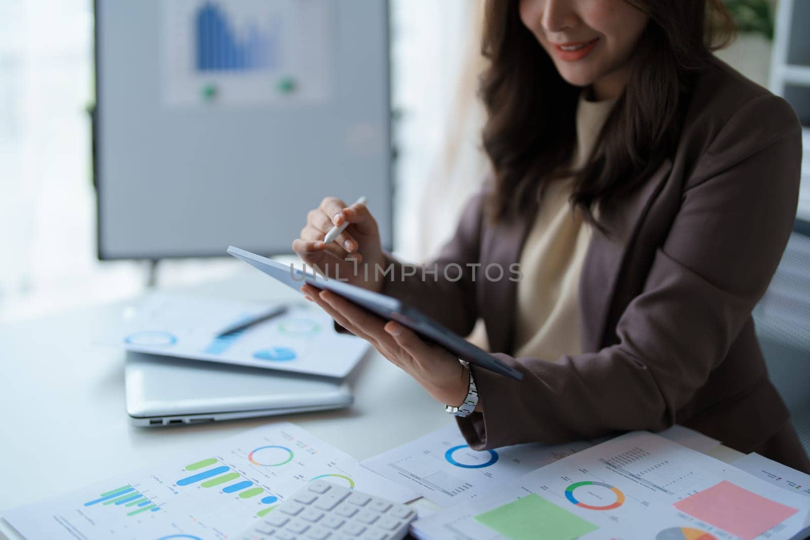 businesswoman in a black suit inside the office using tablet computer, audit paperwork for customers to contact, business people concept