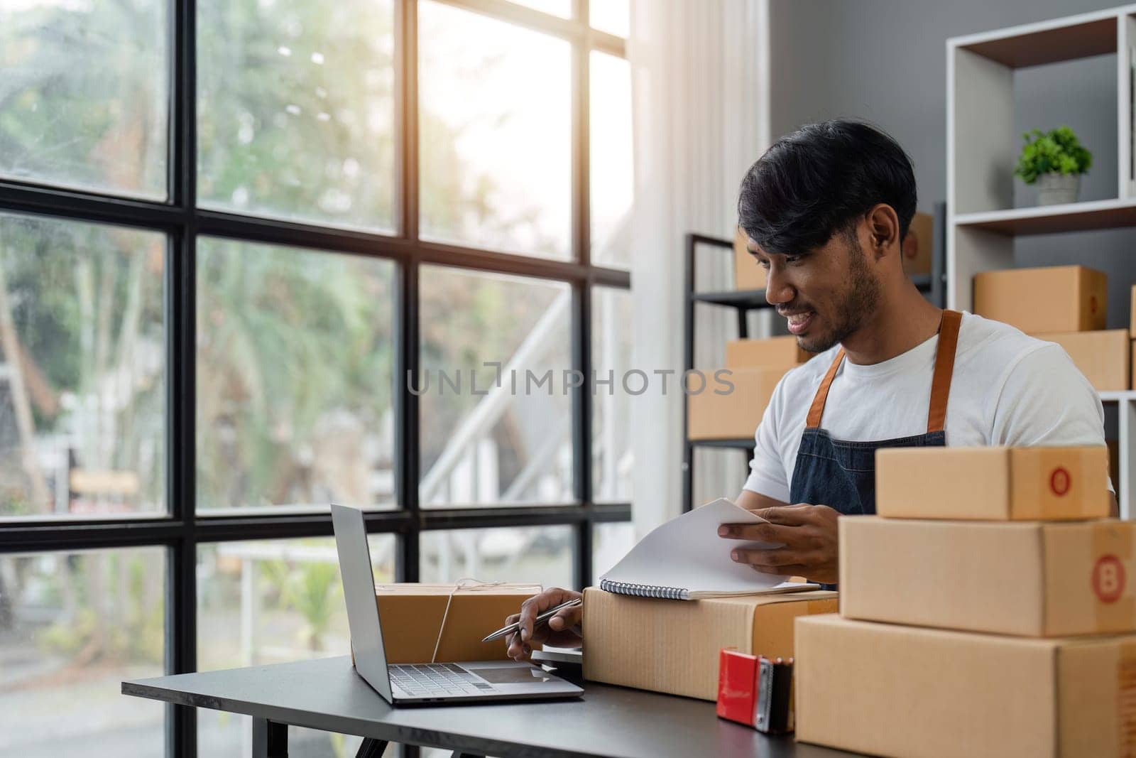 Online business ideas Asian man selling things online holding parcel boxes preparing to deliver to customers with joy.