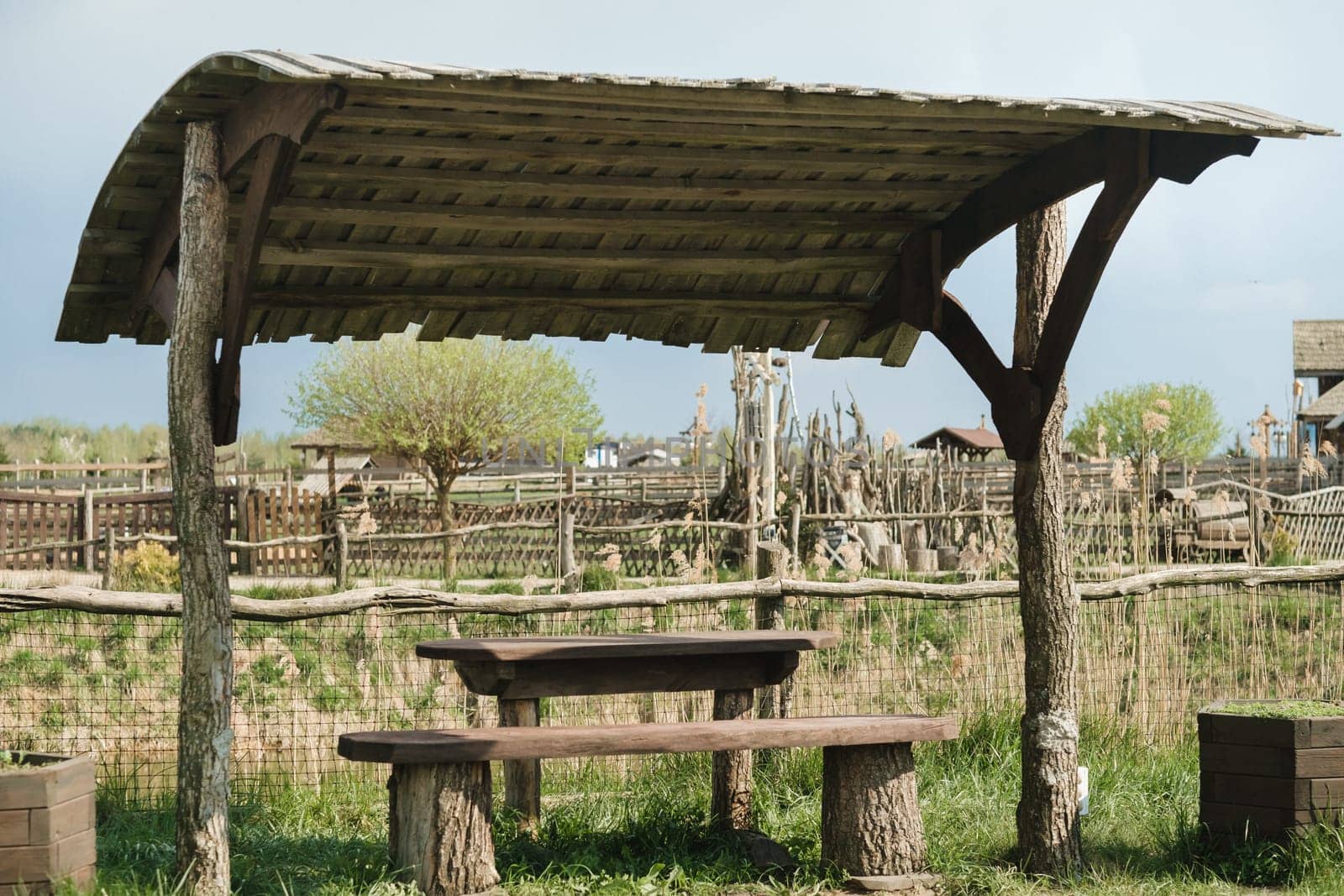 An old wooden gazebo for relaxing in the park. Equipped with wooden tables and benches.