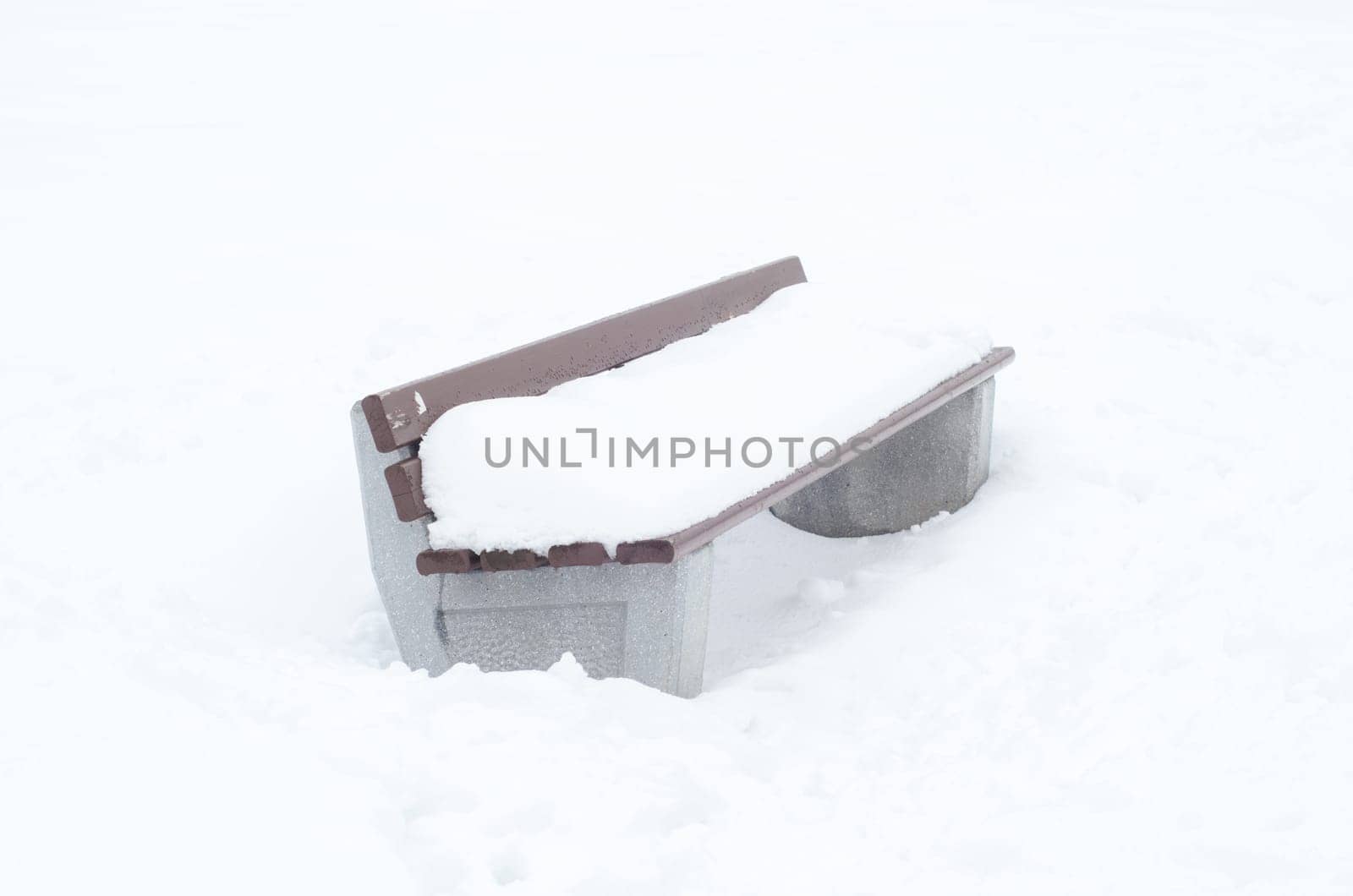 A bench in the park covered with snow in winter. Winter weather and first snow concept.