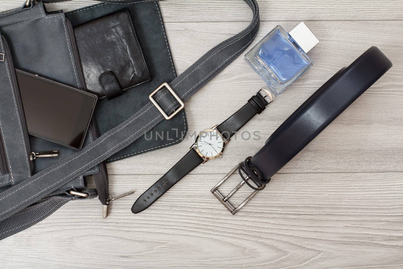 Leather shoulder bag for men with mobile phone and wristwatch on gray background. by mvg6894
