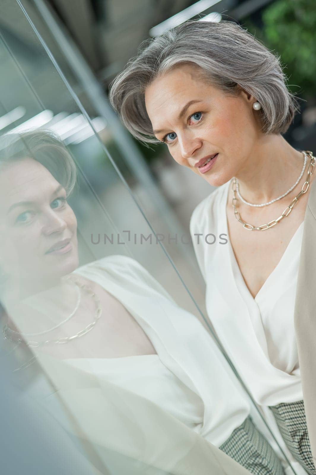 Portrait of a beautiful gray-haired caucasian woman at the glass door. by mrwed54