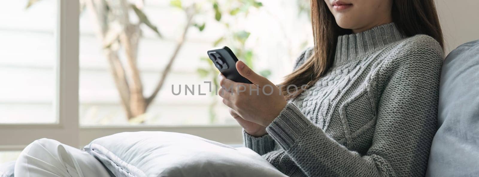 Young asian woman using mobile phone. Social media messaging Woman sitting on sofa playing with phone.