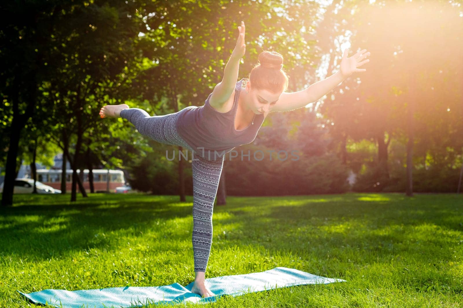 Young fitness woman meditation in a city park.Yoga at sunset in the park. Girl is practicing yoga. Fitness training outdoors. Attractive fitness woman. Workout outdoors. Healthy lifestyle. sun flare