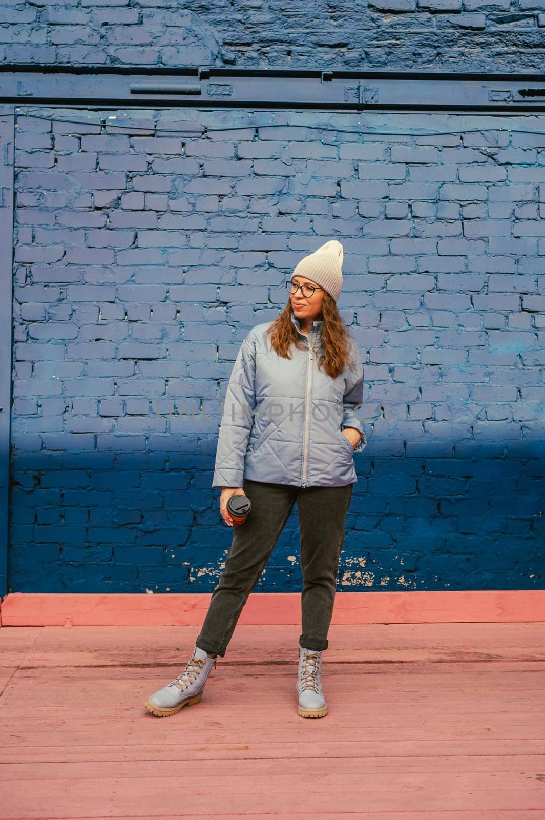 Portrait of a stylish woman in blue jacket with coffee cup. Spring outdoor portrait.