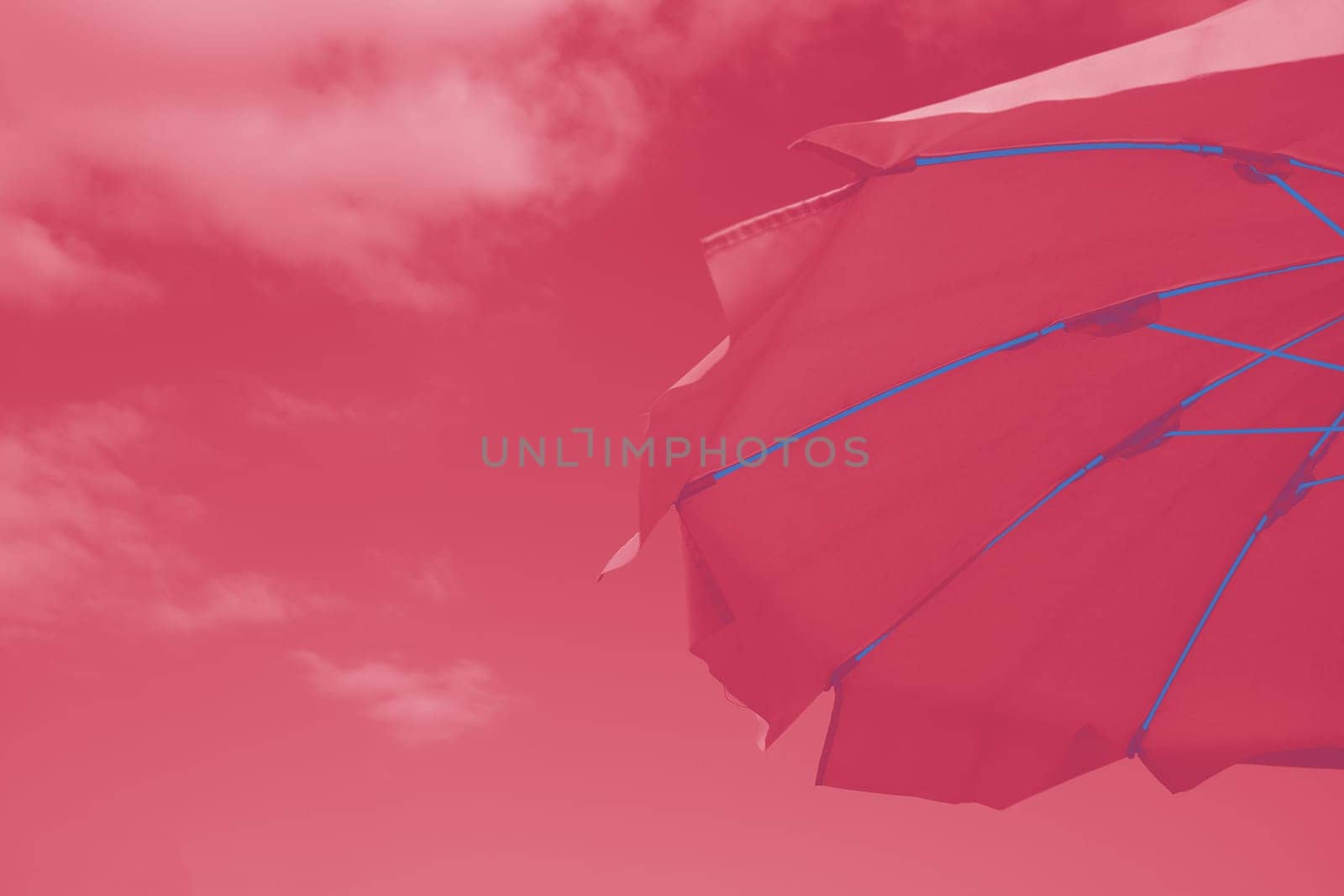 Pretty vibrant pink beach umbrella on the beautiful golden sand of an idyllic tropical beach conceptual of a summer vacation or getaway