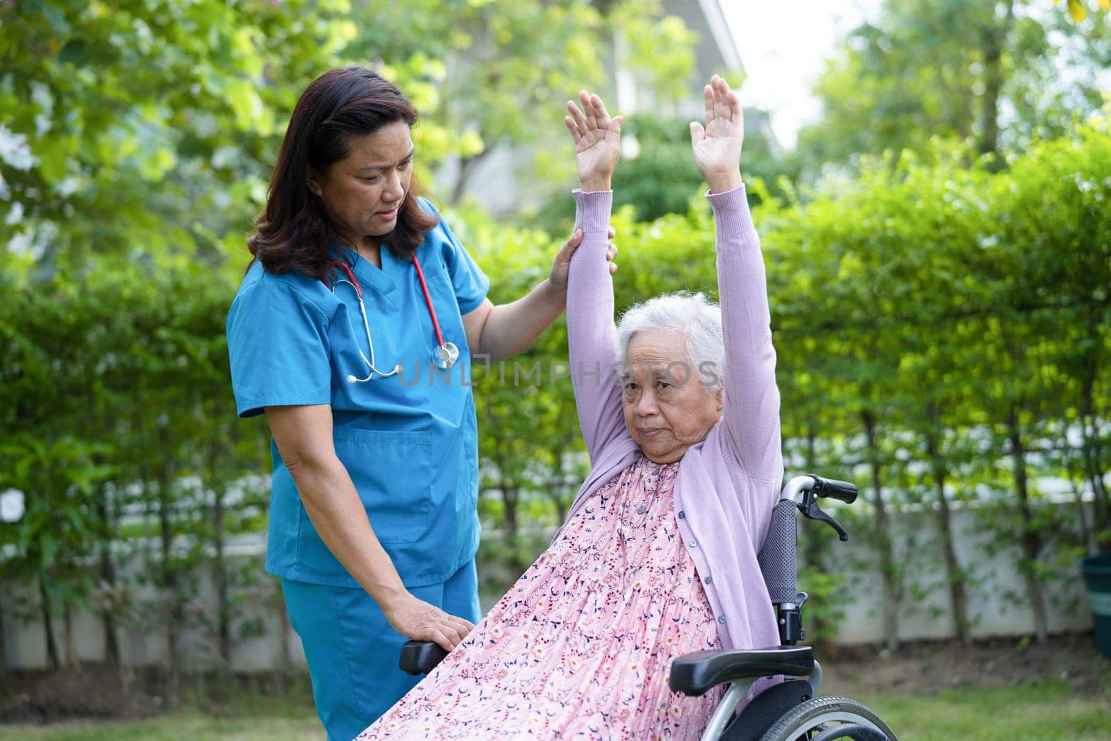 Doctor help and care Asian senior woman patient exercise in the morning on wheelchair at park in hospital.