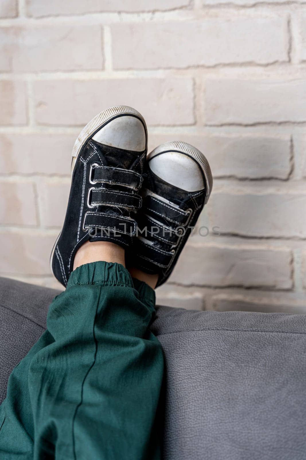 Relaxed legs of a boy in comfortable sneakers on a cozy sofa by audiznam2609