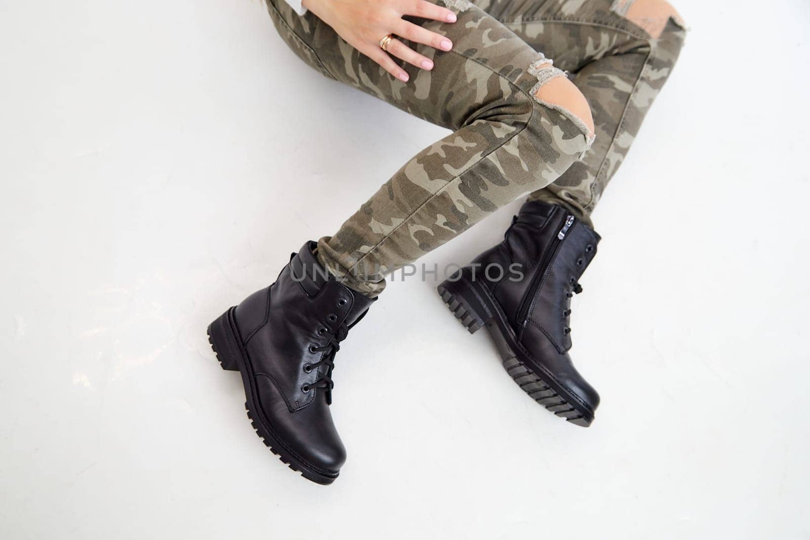 Female winter, autumn or spring black leather shoes on leg of woman in studio on white background. Fashionable modern photography and photoshoot for store, catalog, magazine or online