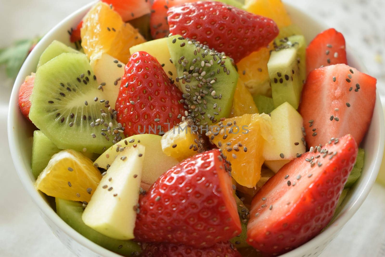 Bowl of fresh fruit salad, kiwi, apples, oranges.