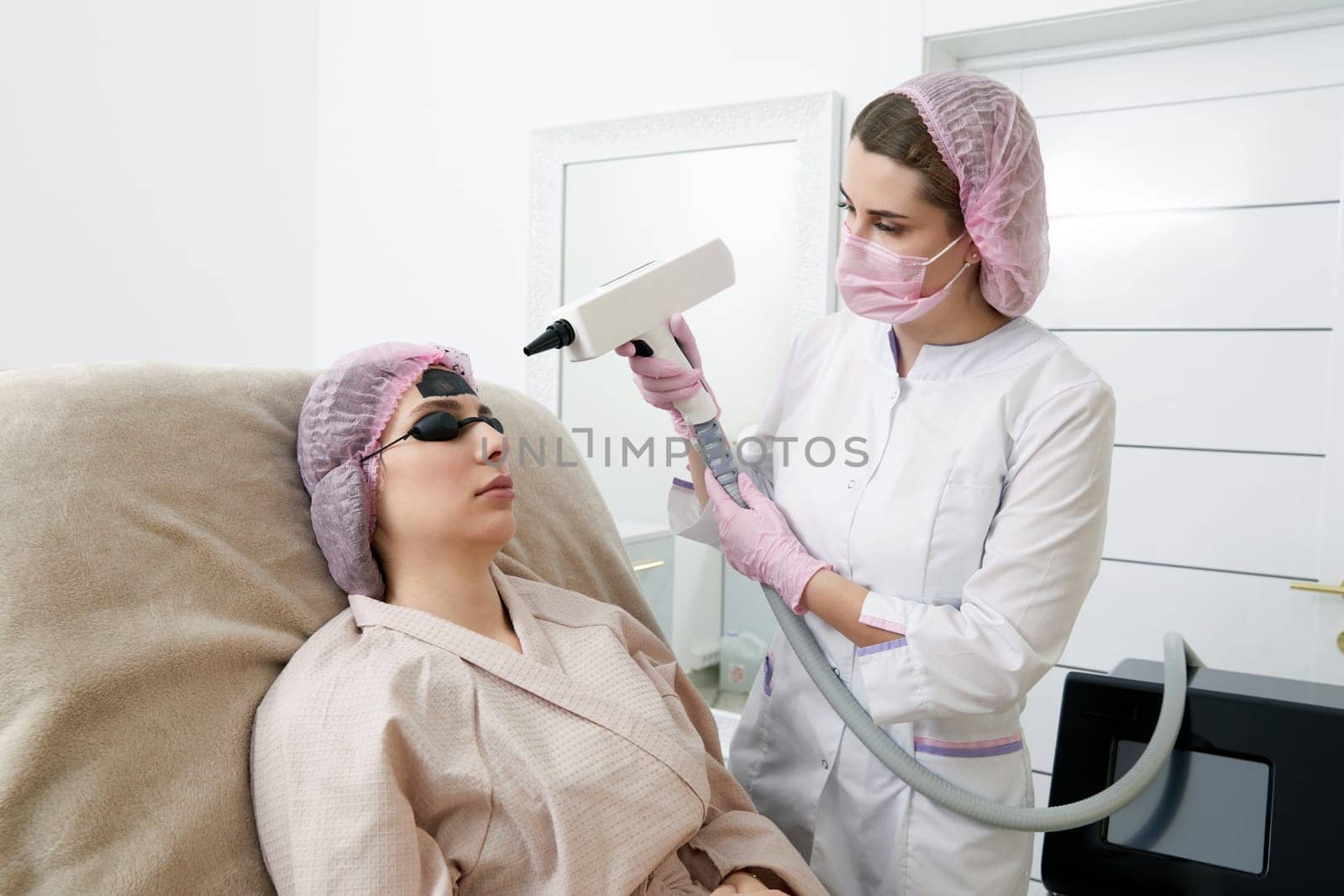 Carbon peeling in beauty salon. Cosmetologist performing carbon peeling to a young woman by Mariakray