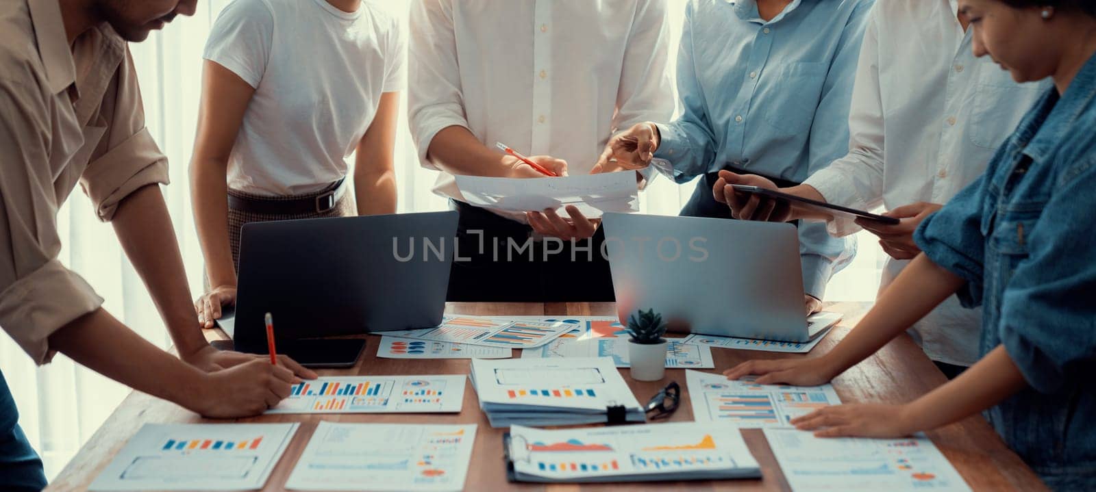 Analyst team utilizing BI Fintech to analyze and pointing at financial dashboard paper office. Businesspeople examining report paper on table for business insight. Panorama shot. Scrutinize