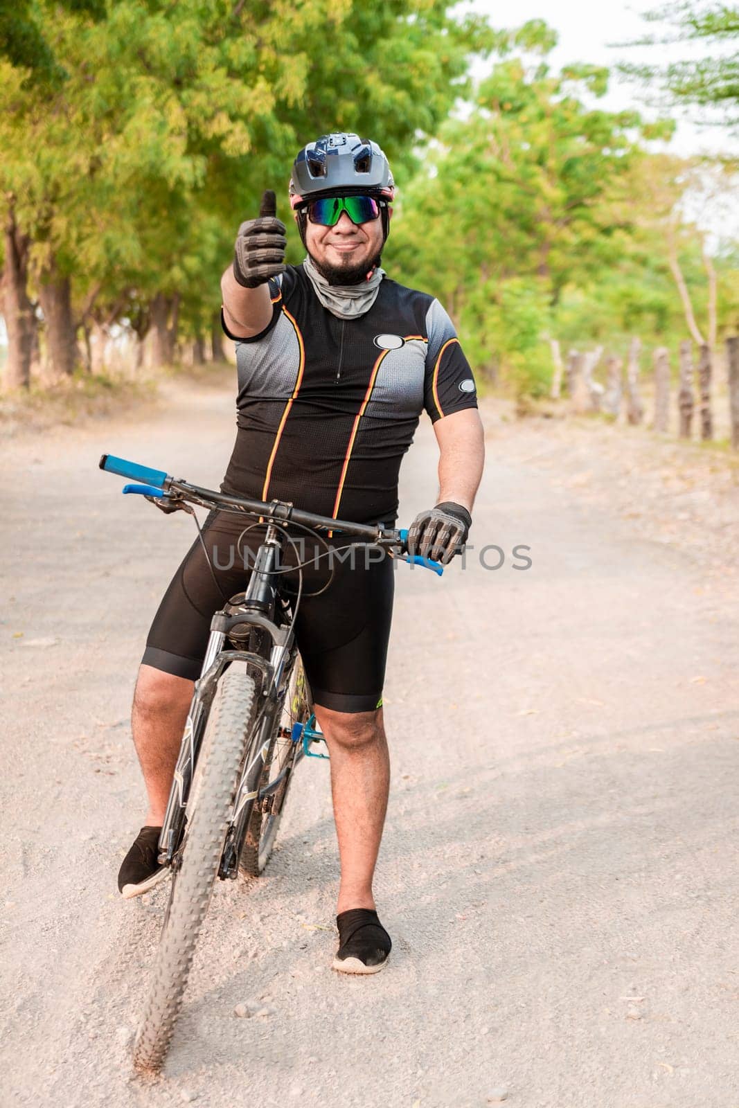 Cyclist giving thumbs up on a road. Professional cyclist doing ok gesture on his bike