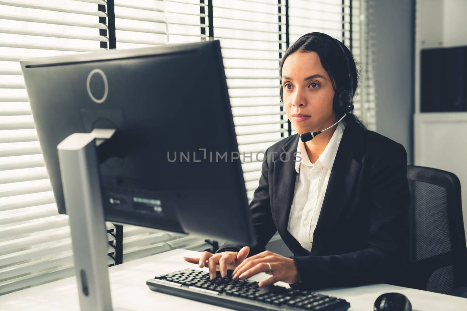 Competent female operator working on computer and talking with clients. Concept relevant to both call centers and customer service offices.