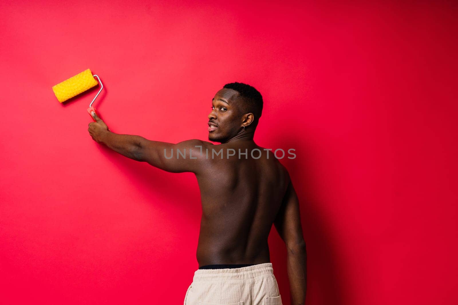 African-American painter on a red studio background topless