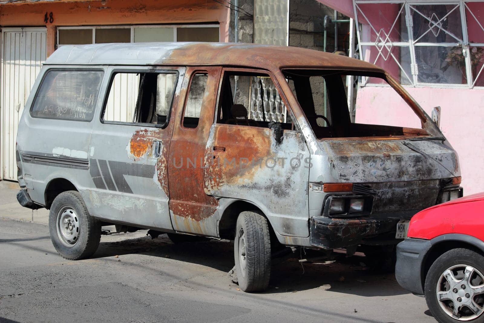 Mexico City, Mexico, October 2019. Burned out car by the side of the road. Nobody in the vehicle.