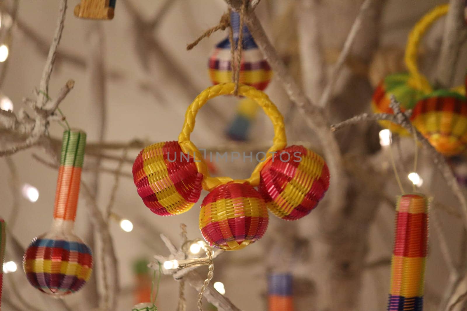 Decorative colorful reed Christmas ornament, hanging in a white brenched tree.