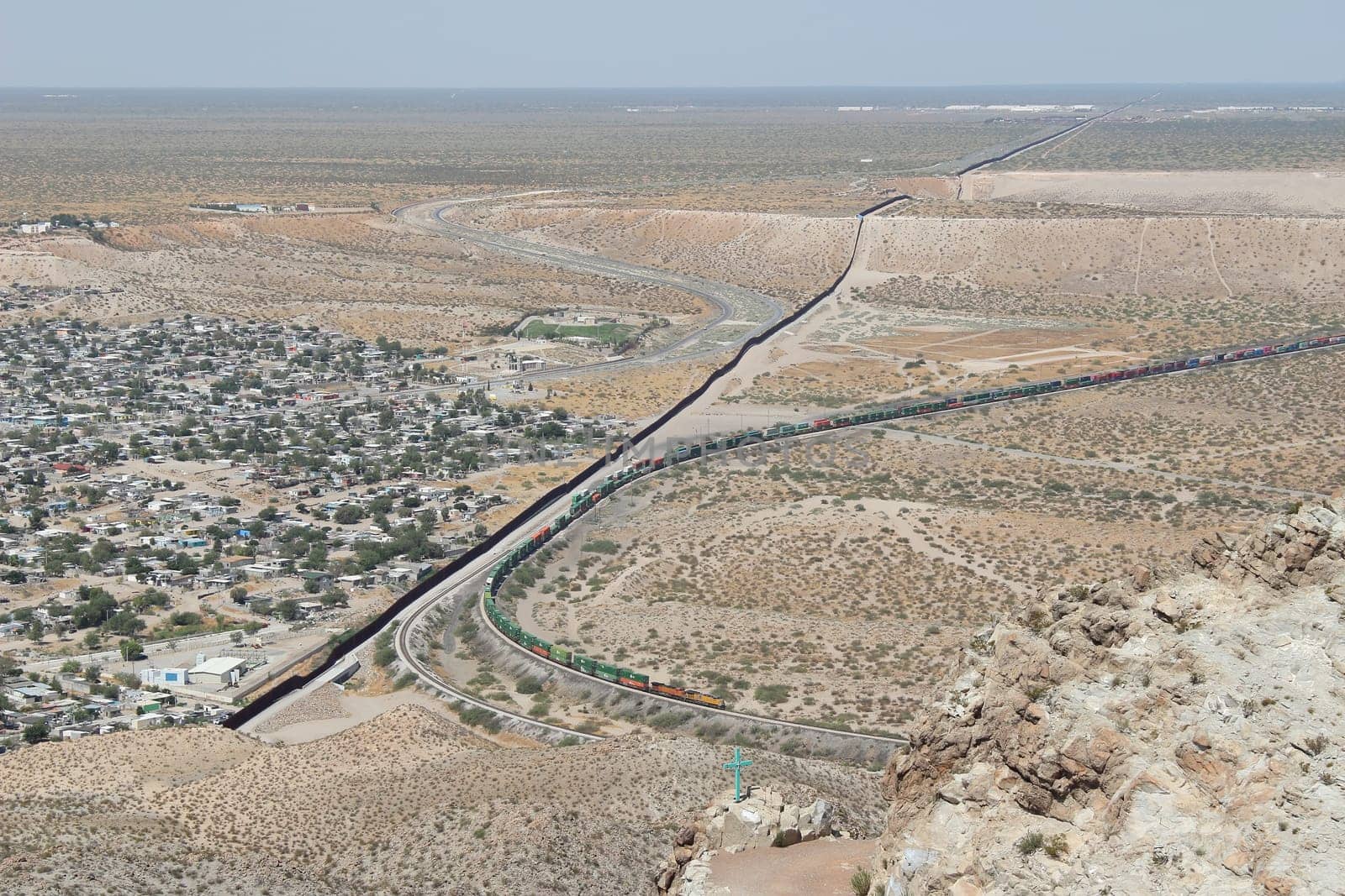 Border wall or fence and train, New Mexico running parallel to freight train on U.S. side of border by Marcielito