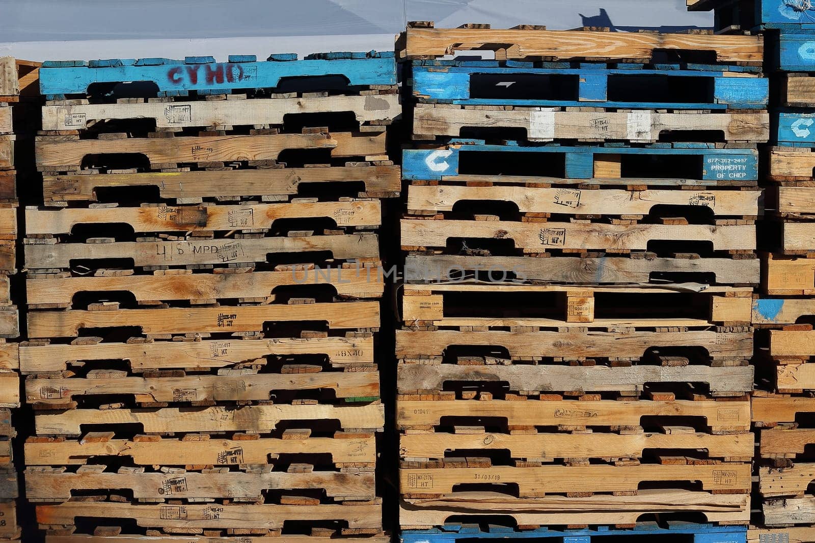 cargo and shipping concept : Stack of colorful rough wooden pallets background at warehouse.