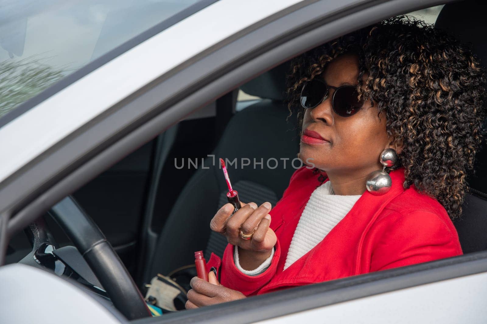 Pretty african american woman in a car doing makeup while standing in a traffic jam, concept a modern married business woman with children saves time, High quality photo