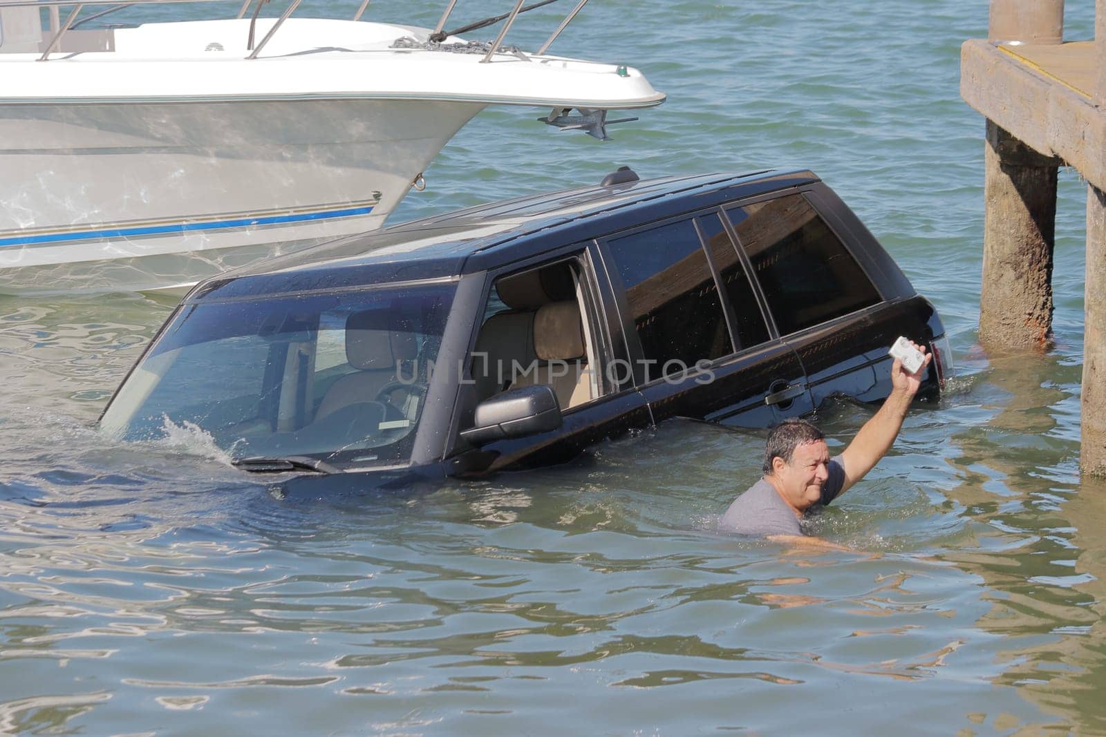 Car submerged in water in front of boats in Miami bay.