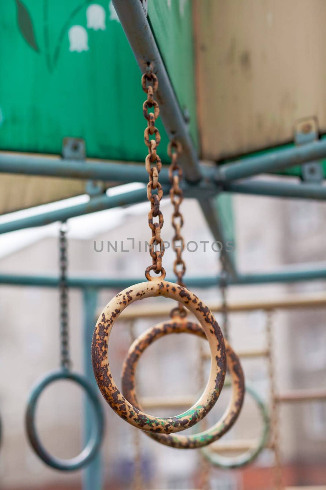 An iron chain with gray and translucent oval rings on a gray background in the courtyard of a multi-storey building. A place of rest and activities for children