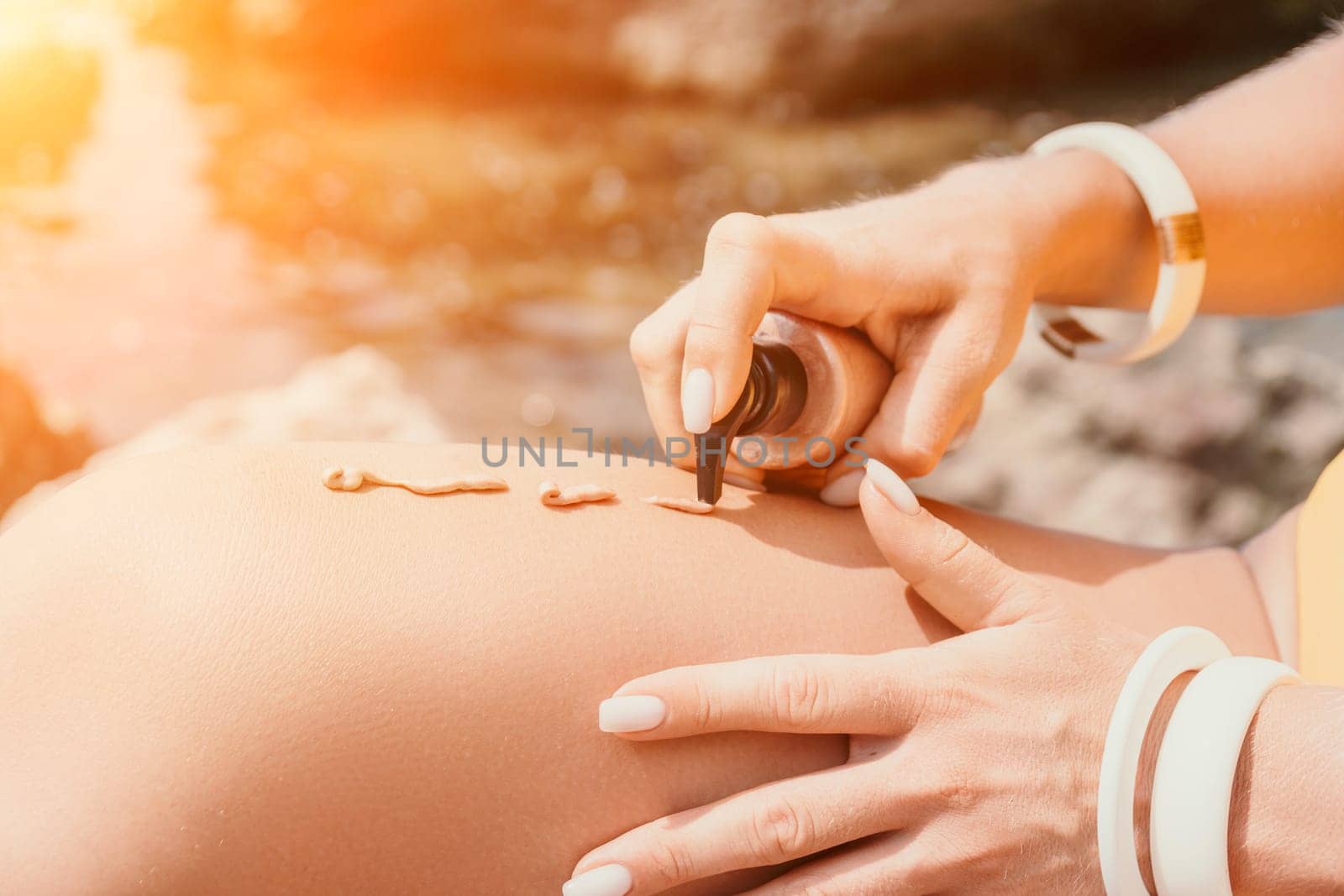 Sexy Woman in bikini apply sun protection cream on her smooth tanned legs. Skin care. Legs on the beach. Portrait of female in hat smearing moisturizing lotion. Sunblock concept.