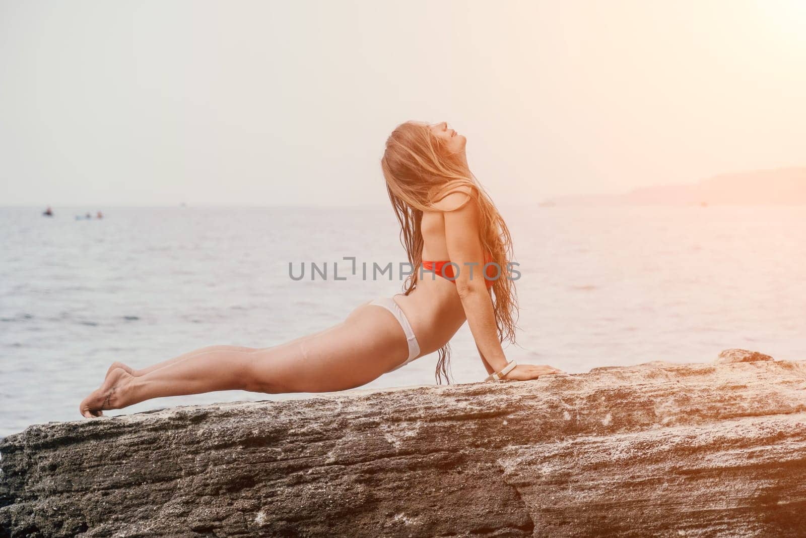 Woman sea yoga. Back view of free calm bliss satisfied woman with long hair standing on top rock with yoga position against of sky by the sea. Healthy lifestyle outdoors in nature, fitness concept. by panophotograph