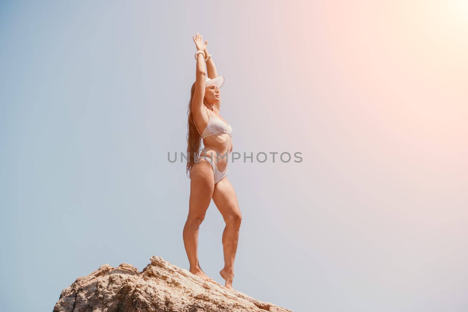 Woman sea yoga. Back view of free calm bliss satisfied woman with long hair standing on top rock with yoga position against of sky by the sea. Healthy lifestyle outdoors in nature, fitness concept. by panophotograph