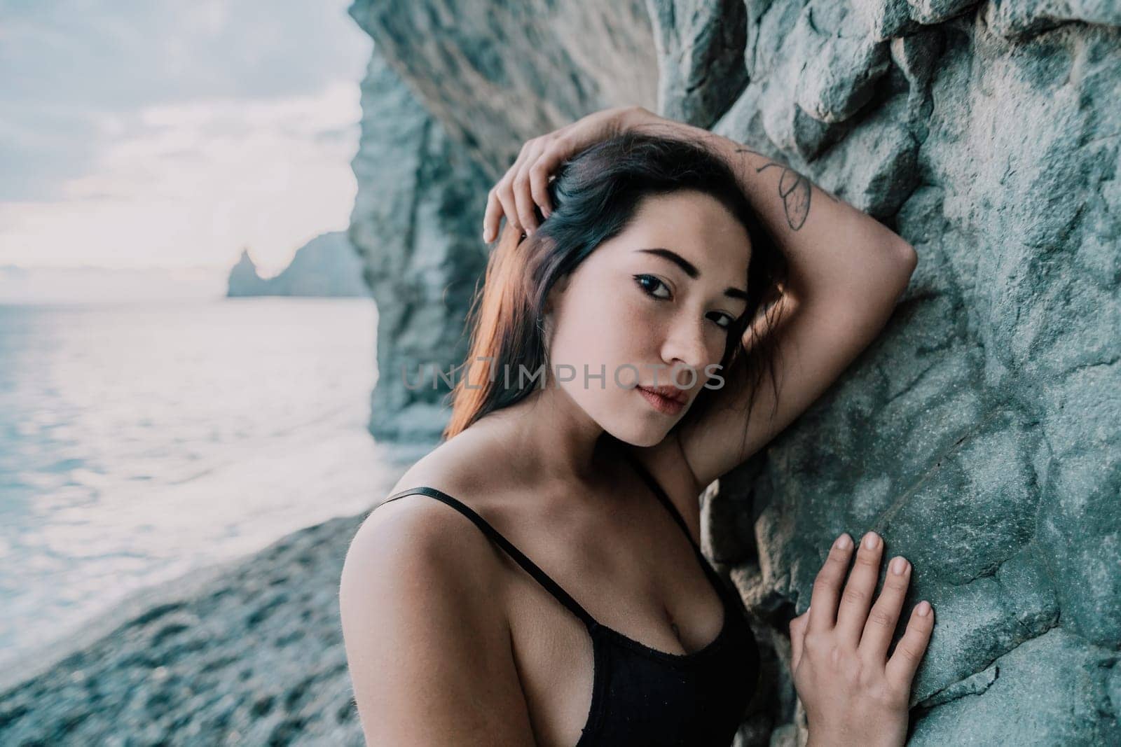 Portrait of cheerful female climber resting on a volcanic basalt by panophotograph