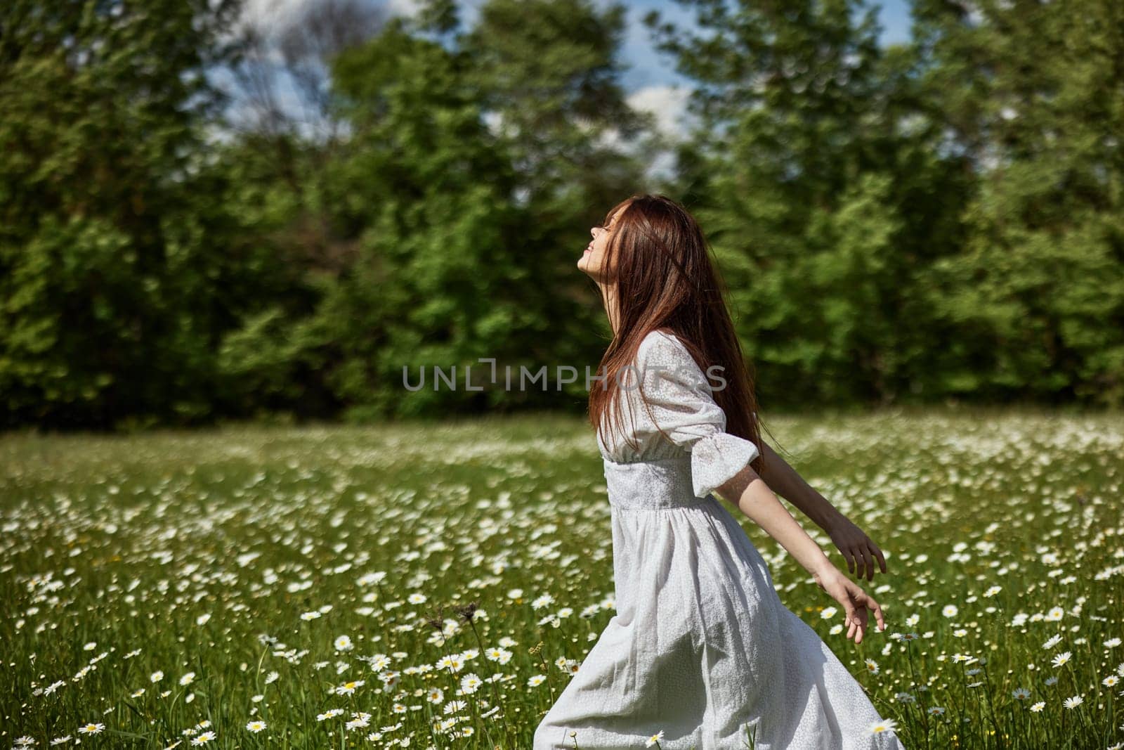 portrait of a free woman in a light dress in a chamomile field against the backdrop of hills enjoying nature by Vichizh