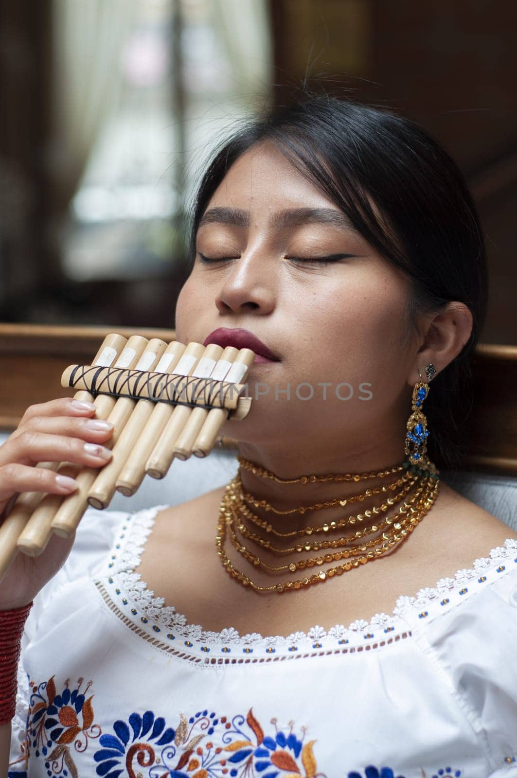 closeup of indigenous woman playing an andean flute with her eyes closed feeling the notes. High quality photo