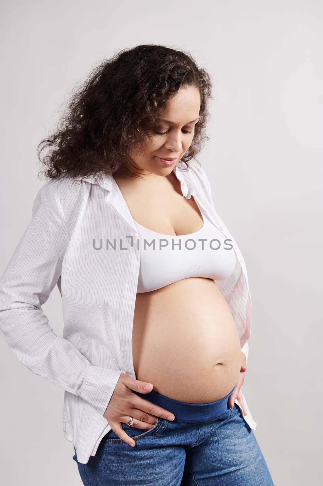 Beautiful curly haired multi ethnic pregnant woman with naked belly, isolated on background. Pregnancy 6 month. 24 weeks by artgf