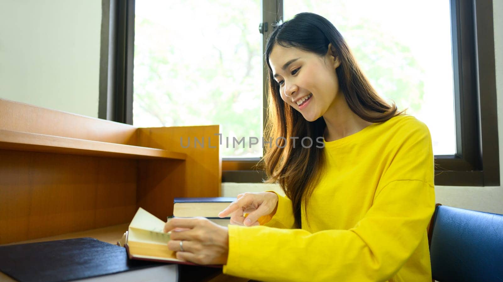 Peaceful woman reading interesting book, preparing for exam in library. People, knowledge and education concept.
