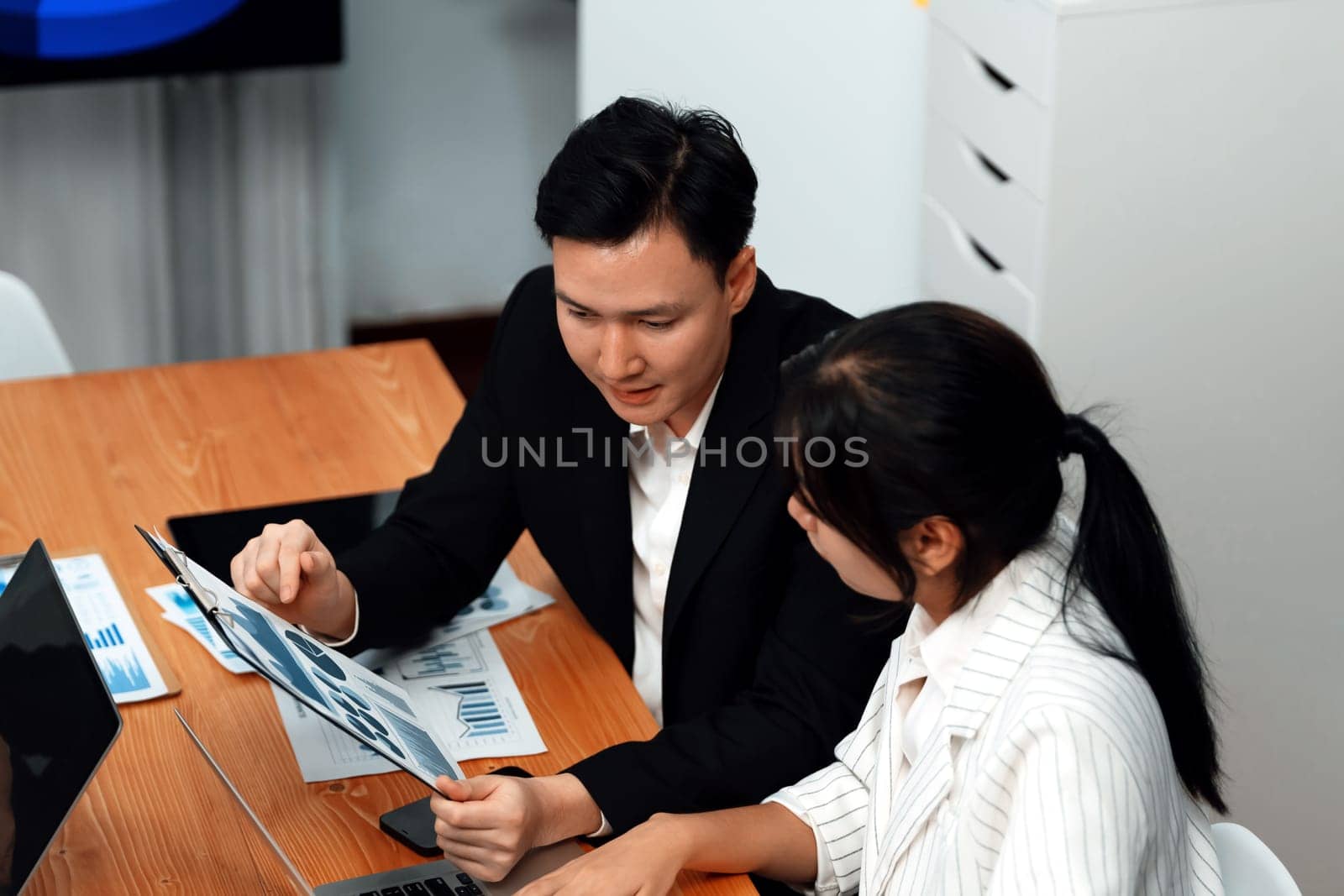 Office worker and manager analyze financial report paper in harmony workplace. by biancoblue