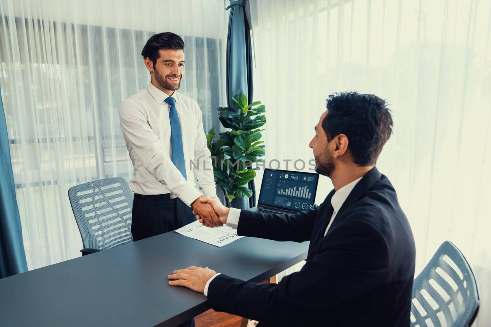 Successful job interview at business office with handshake. Positive discussion of qualifications and application for position. Job hiring concept between candidate and interviewer. Fervent