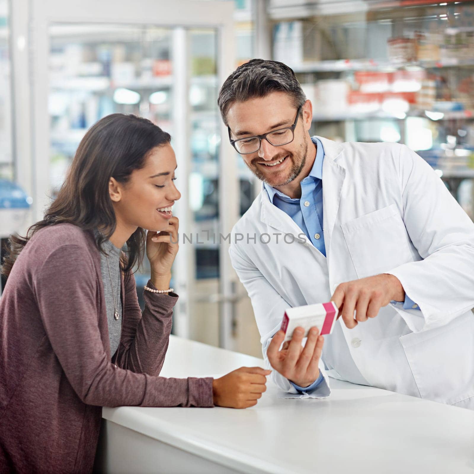 a male pharmacist assisting a customer at the prescription counter. All products have been altered to be void of copyright infringements by YuriArcurs