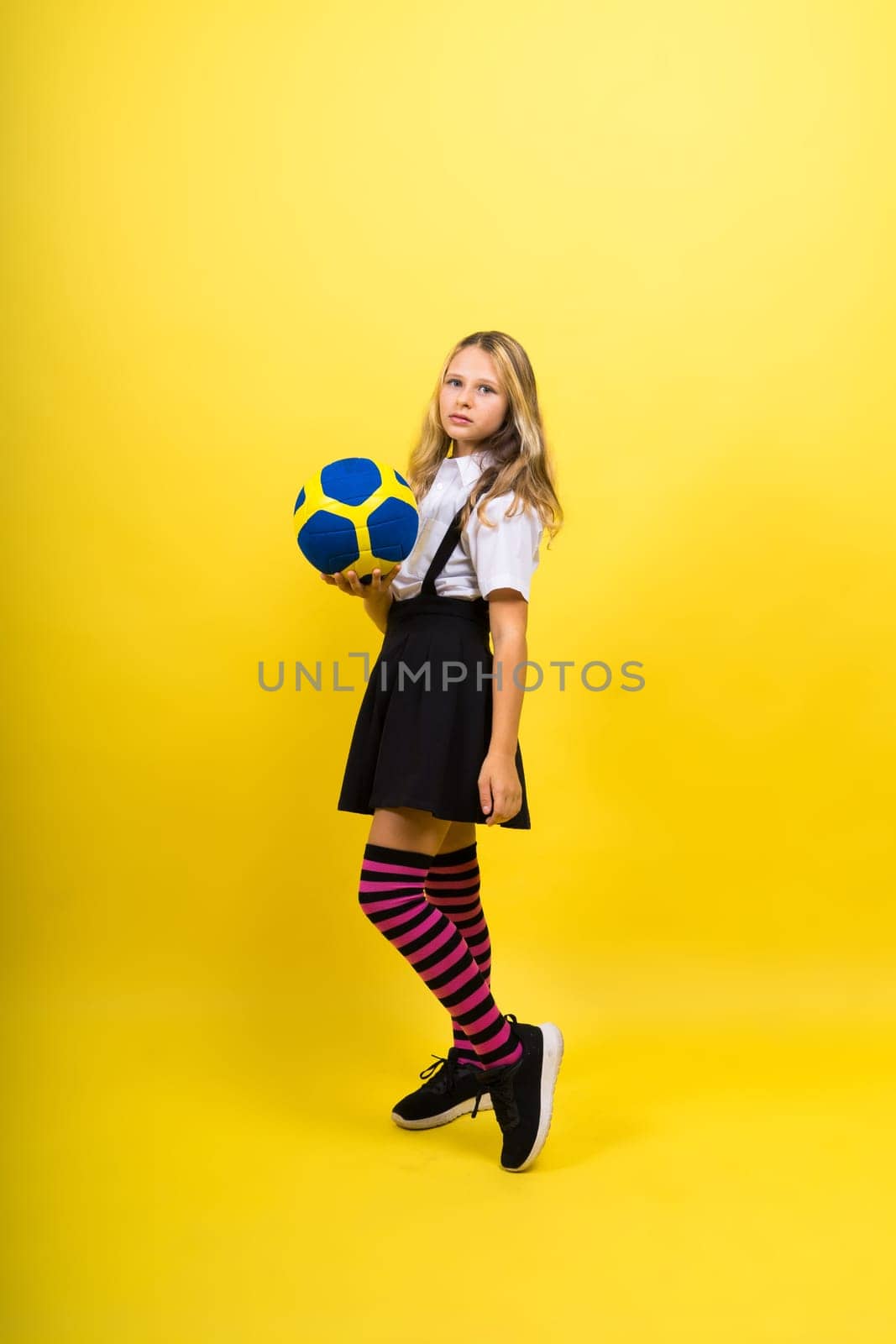 Portrait of a cute eight year old girl in volleyball outfit isolated on red yellow background by Zelenin